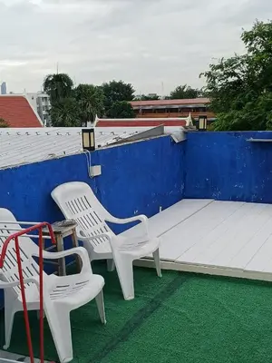 two white chairs and a bed on a roof at Sleepwith me Hostel in Bangkok