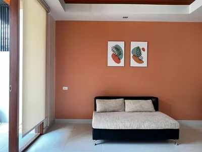 a bed in a room with an orange wall at Smile Residence at Kaset-Sena in Ban Yang
