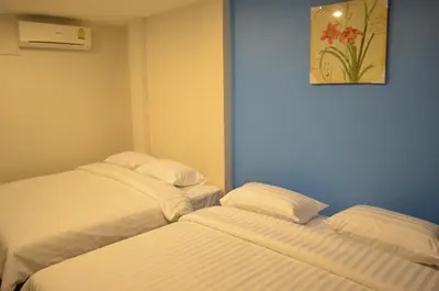 two beds in a room with white sheets at Varinda Hostel in Bangkok