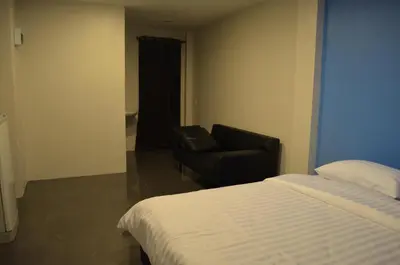 a bedroom with a bed and a chair and a couch at Varinda Hostel in Bangkok