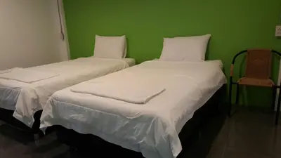 two beds in a room with a green wall at Varinda Hostel in Bangkok