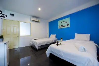 a room with two beds and a blue wall at Varinda Hostel in Bangkok