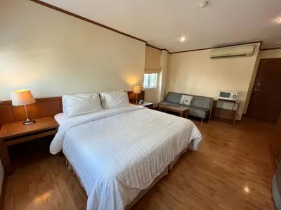 a bedroom with a large white bed and a living room at Jhouse Thonglor in Khlong Toei