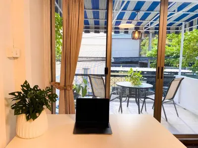 a laptop on a table in a room with a balcony at Flip Flop In Townhouse in Bangkok