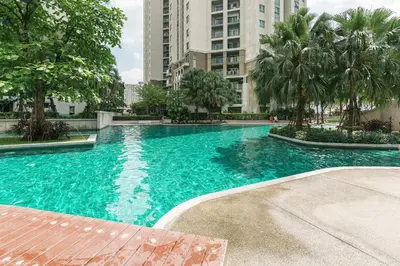 a large blue swimming pool with trees and buildings at MRT rame9 Jodd Fairs night market, walk for a few minutes, two bedrooms and two bathrooms in Ban Don Sai
