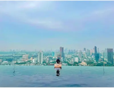 a woman standing in the water at the edge of the skyraper at 2 Bedroom Luxury Apartment 3 min walk from BTS Ekkamai in Bangkok