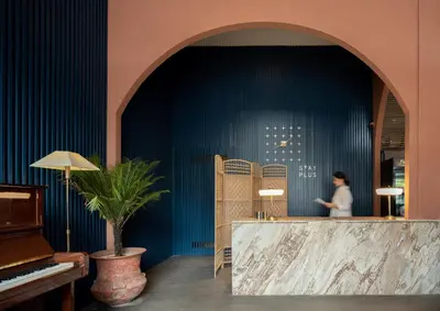 a woman walking in a room with a blue wall at Stay Plus Hotel Bangkok in Bangkok