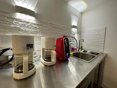 a kitchen counter with two coffee machines and a sink at The White Den Sukhumvit 44 in Bangkok