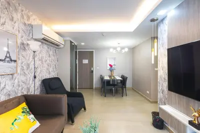 a living room with a couch and a tv and a table at Dazzle Sukhumvit 7 by LeFoyer in Bangkok