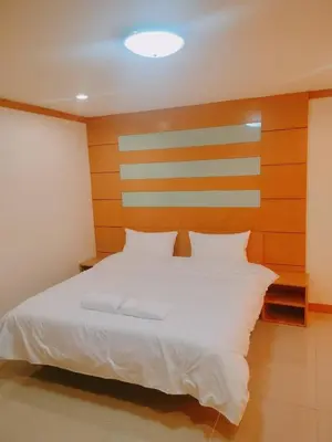 a bedroom with a white bed with a wooden headboard at Love mansion in Bangkok