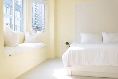 a white bedroom with a bed and a window at Baan Khun Pra APT No4 Duplex 3BR in Bangkok