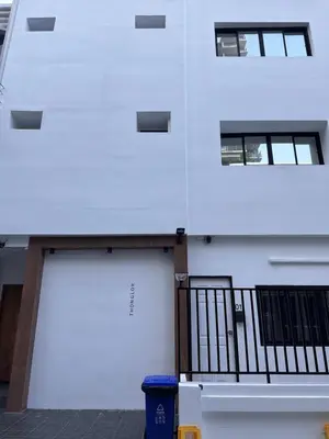 a building with two garage doors and a trash can at Dado9home in Khlong Toei