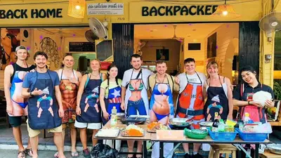 a group of people in aprons standing in front of a table at Back Home Backpackers Hostel in Bangkok