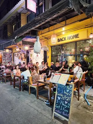 a group of people sitting at tables outside a restaurant at Back Home Backpackers Hostel in Bangkok