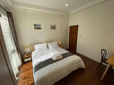 a bedroom with a large bed with white sheets at 1 min walk to BTS, 3 Bed 3 Bath, Entire House in Bangkok