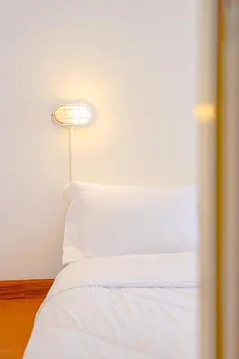 a bedroom with a white bed with a lamp at PICCOLO SUKHUMVIT HOSTEL- Self check-in after 6 pm in Bangkok