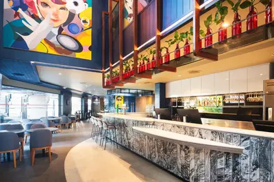 a restaurant with a bar with chairs and tables at Lumen Bangkok Udomsuk Station in Bangkok