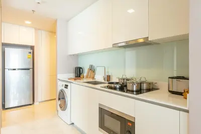 a kitchen with white cabinets and a washer and dryer at The Pinnacle Sukhumvit 11 by LeFoyer in Bangkok