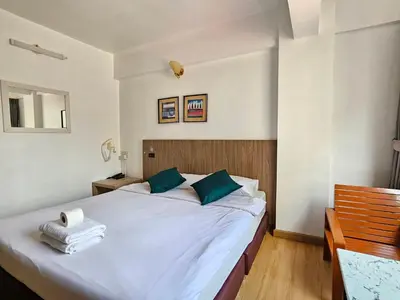 a bedroom with a large white bed with blue pillows at Crown BTS Nana Hotel in Bangkok