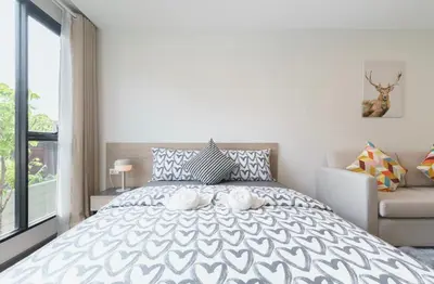a bedroom with a bed with a white and gray comforter at Sathon-Charoen Nakhon Condo in Bangkok