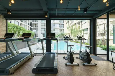 a gym with cardio machines and a swimming pool at Sathon-Charoen Nakhon Condo in Bangkok