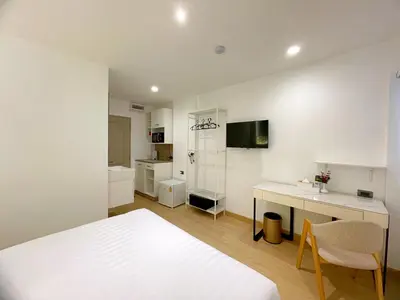a bedroom with a bed and a desk and a kitchen at Arawana Express Sukhumvit 22 in Bangkok