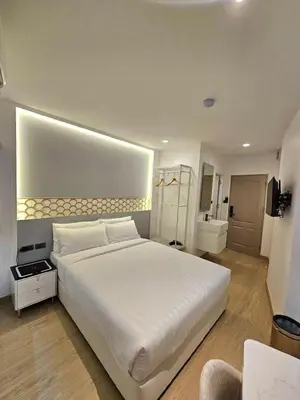 a bedroom with a large white bed and a bathroom at Arawana Express Sukhumvit 22 in Bangkok
