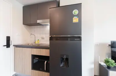 a black refrigerator in a kitchen with a sink at \u6c99\u541eSathon-Charoen Nakhon\u7cbe\u54c1\u516c\u5bd3 in Bangkok