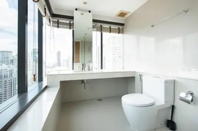 a white bathroom with a toilet and large windows at M Estate Private Residence 3BR, Heart of Bangkok in Bangkok