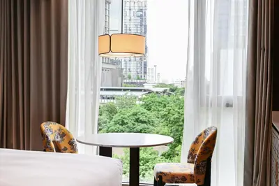 a room with a bed and a window with a table and chairs at Madi Paidi Bangkok, Autograph Collection in Bangkok