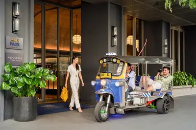 a woman standing next to a man riding a golf cart at Madi Paidi Bangkok, Autograph Collection in Bangkok