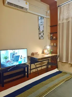 a living room with a flat screen tv and a desk at Be Local BNB in Bangkok