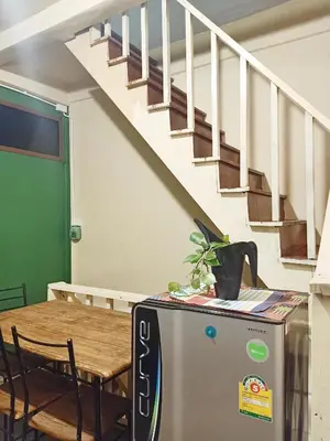 a room with a table and a refrigerator and a staircase at Be Local BNB in Bangkok