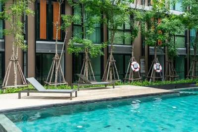 a pool with two lounge chairs and a building at Bts thonglo 700m free wifi & gym in Ban Hua Khao Sisiat