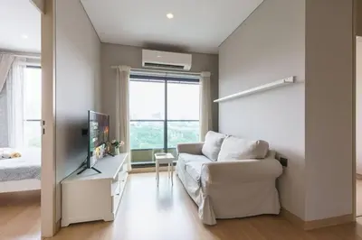 a living room with a couch and a tv and a bed at Lumpini Suite Phetchaburi Siam Square Nana in Ban Non Phatthana