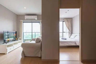 a bedroom with a bed and a tv and a couch at Lumpini Suite Phetchaburi Siam Square Nana in Ban Non Phatthana