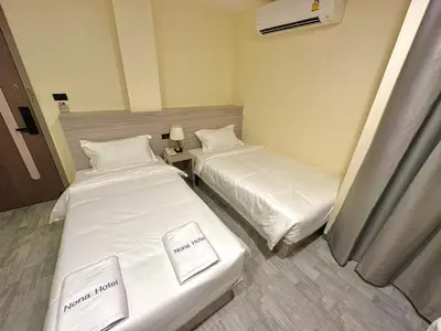 two beds in a hotel room with white sheets at Nona Hotel, Bangkok in Makkasan