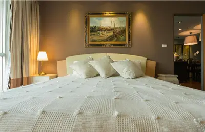 a large white bed in a bedroom with a painting on the wall at Sukhumvit Boutique Suite : Soi 13/ 10min. from BTS Nana station in Bangkok