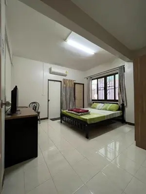 a bedroom with a bed and a desk and a window at Pimravee Apartment (Yaek 8) in Ban Zong Katiam