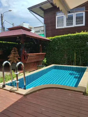 a swimming pool in front of a house at Aran Cottage Ngamwongwan The Pool Villa in japanese Garden in Nonthaburi
