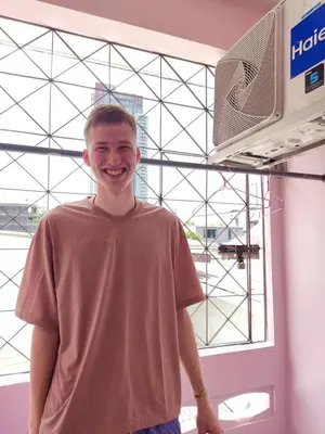 a young man standing in front of a window at Worakarn Apartment 3 in Bangkok