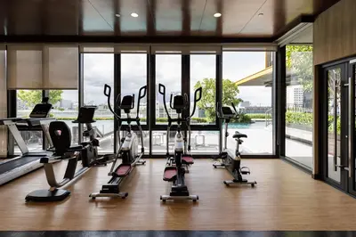 a gym with treadmills and ellipticals in a room with windows at Bangkok city center-thong lo-rca-high-rise one-bedroom in Bangkok