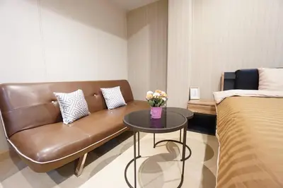 a living room with a couch and a table with flowers at Maruay Living Apartment (Khaosan/Chinatown/Samyot MRT) in Bangkok