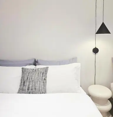 a white bedroom with a white bed and a black lamp at PB home 1 min to BTS Saladaeng & MRT Silom in Bang Rak