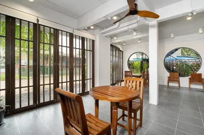 a dining room with a table and chairs and windows at Homie Non - โฮมมี่ นนท์ in Ban Bang Khwang