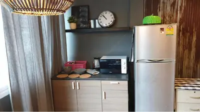 a kitchen with a refrigerator and a clock on the wall at Tuk Tuk House 250m from MRT Sirikit in Bangkok