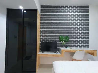 a bedroom with a bed and a tv and a black wall at Irich residence South Samrong 6 Kms BTS-Pu Chao in Samut Prakan