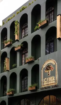 a building with potted plants and a sign on it at Cher Hostel Bangkok in Bangkok