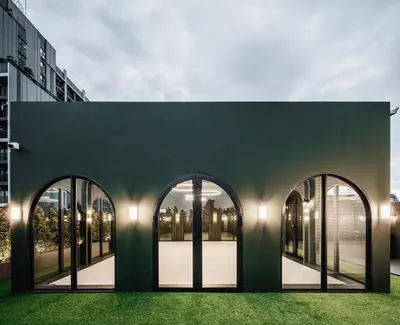 a green building with large windows and green grass at Cher Hostel Bangkok in Bangkok