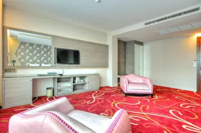 a hotel room with pink chairs and a flat screen tv at One One Bangkok in Bangkok
